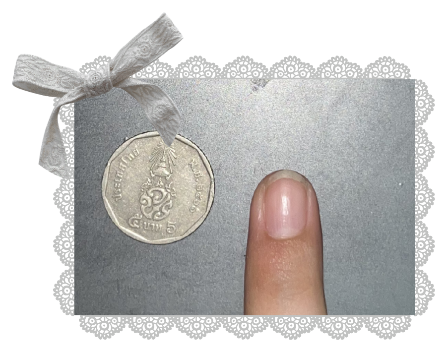 Thai baht coin placed beside a fingernail as a scale reference